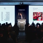 The auctioneer gestured to the crowd during the auction, and the screen showed the prices of different currencies and the image of Basquet's paintings.