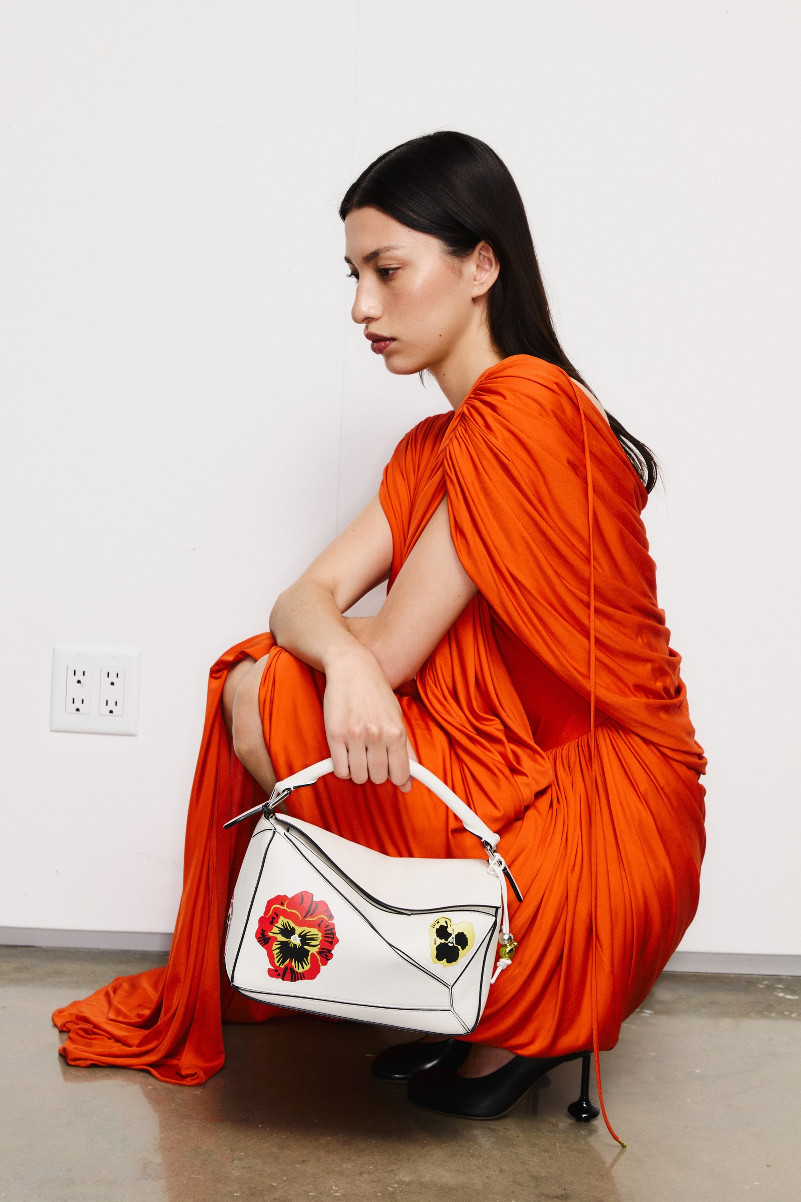 Images may contain accessories bags, handbags, adult wallets, sitting clothes, heels, and dresses