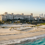 A grand building on the beach by the sea.